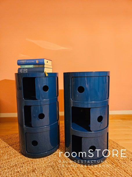 Kartell Container in blau, je 90.- Zwei runde, blaue Aufbewahrungseinheiten mit Fächern und einem Stapel Bücher oben.